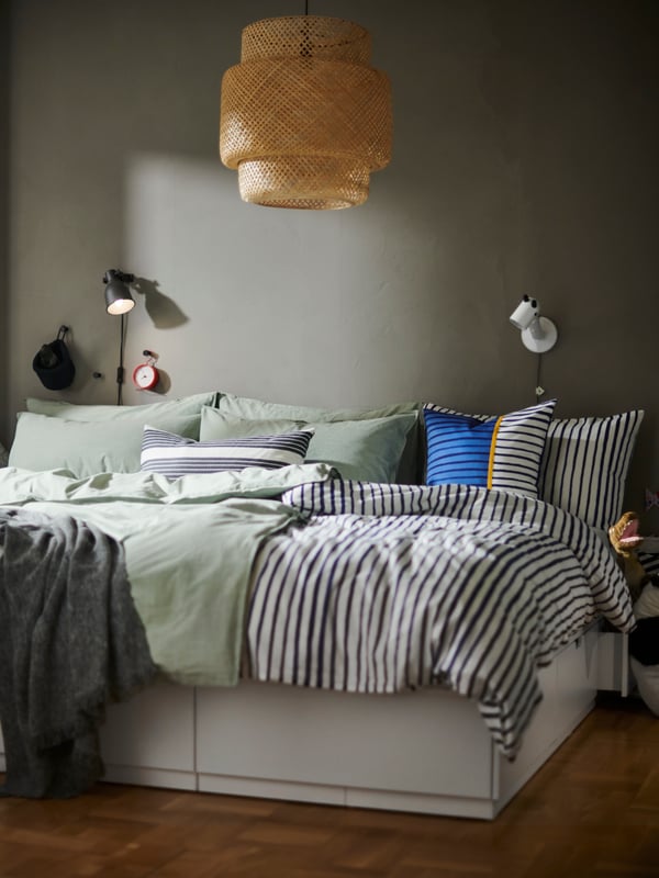 Una struttura letto NORDLI con cassetti, copripiumino e federe SÅNGLÄRKA a righe da un lato e copripiumino e federe BERGPALM verde dall’altro - IKEA