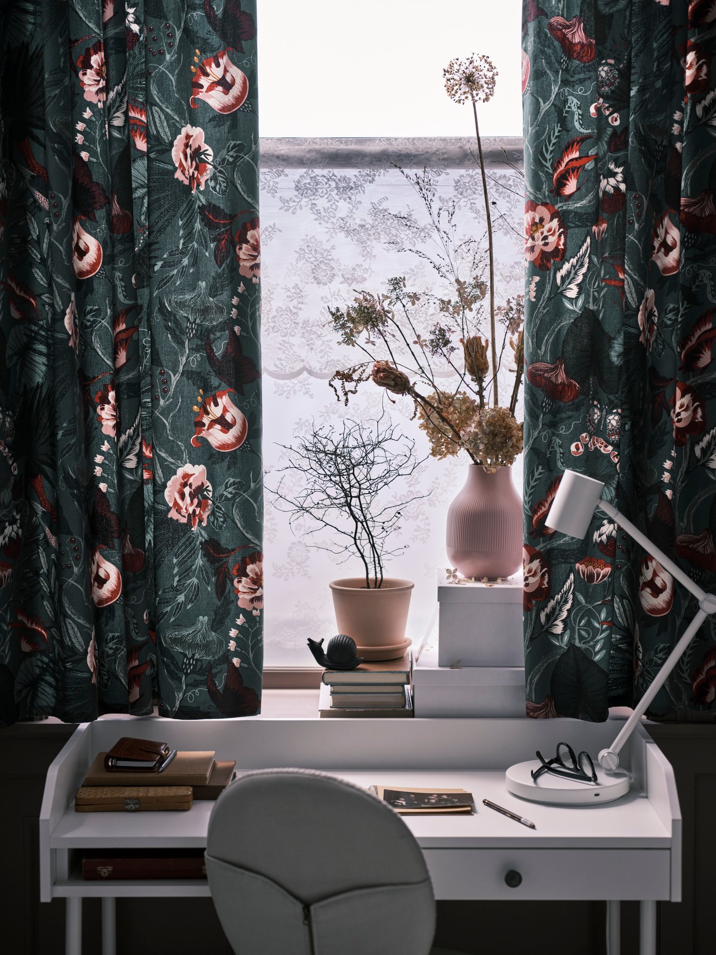 Curtains made with flower patterned FILODENDRON fabric in a window above a white HAUGA desk with a beige swivel chair.