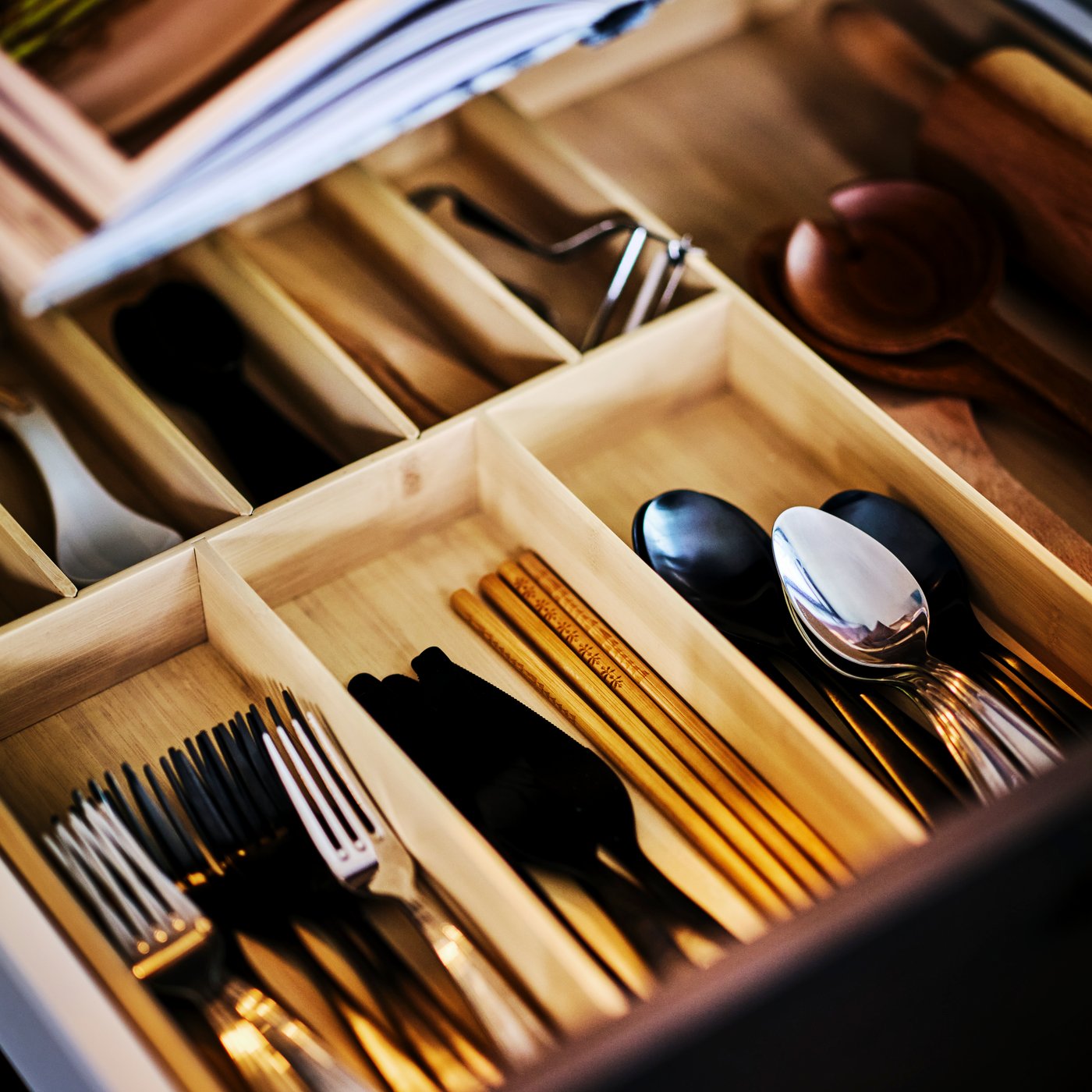 Organized kitchen drawer with utensils, cutlery, spoons, and chopsticks in wooden dividers