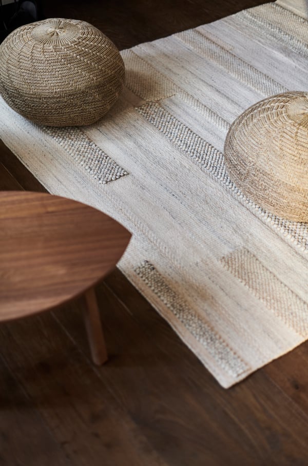 conjunto de pouf sobre una alfombra color blanco.