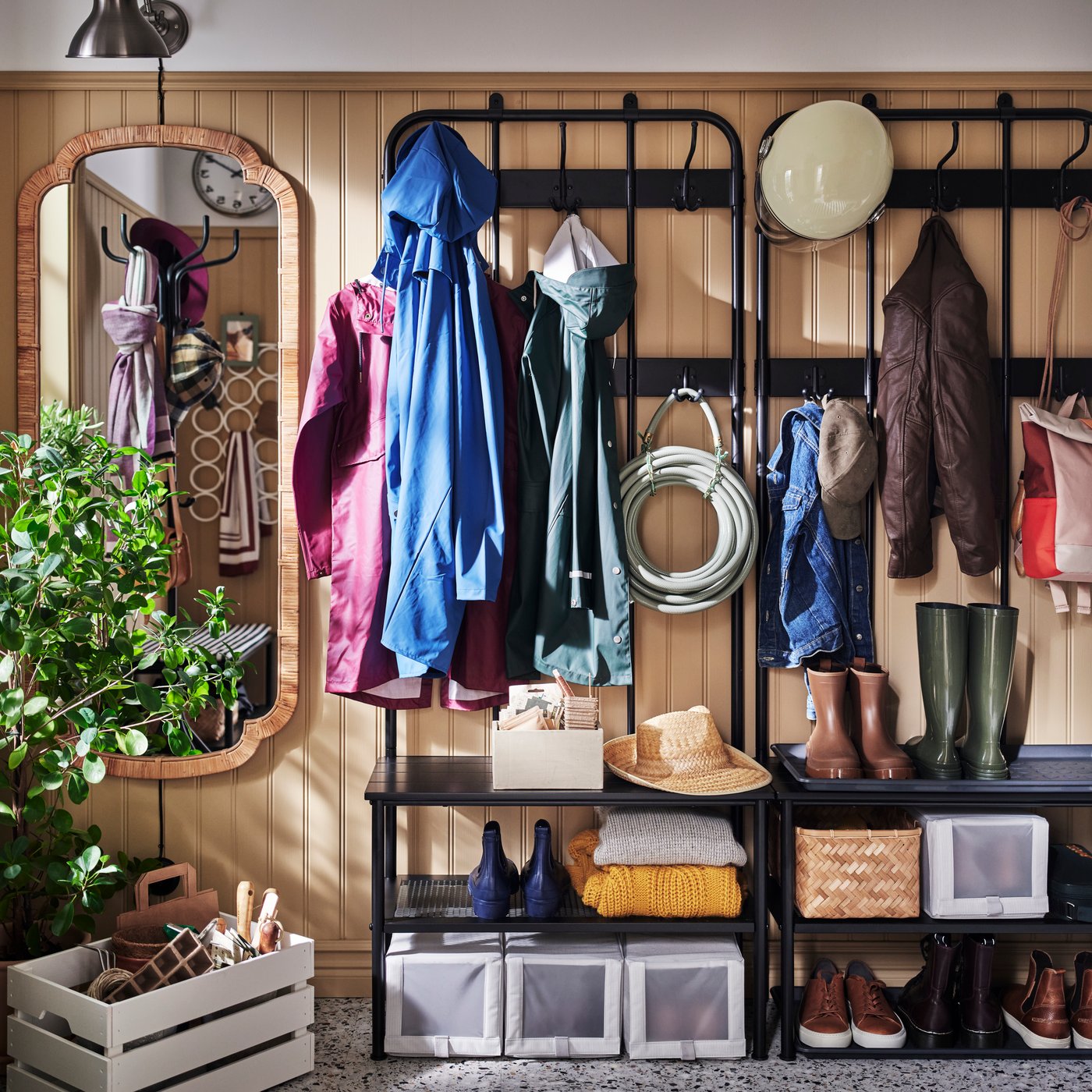 Deux portemanteaux et bancs avec rangement pour chaussures NIPÅSEN noirs dans un vestiaire aux lambris brun clair, avec une boîte KNAGGLIG peinte sur le sol.