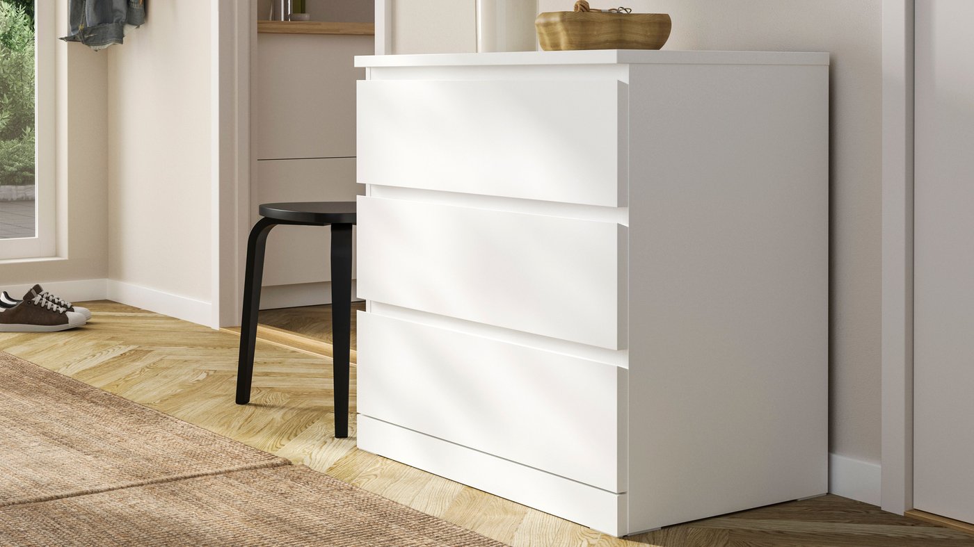 Cómoda blanca MALM con tres cajones junto a pared blanca.