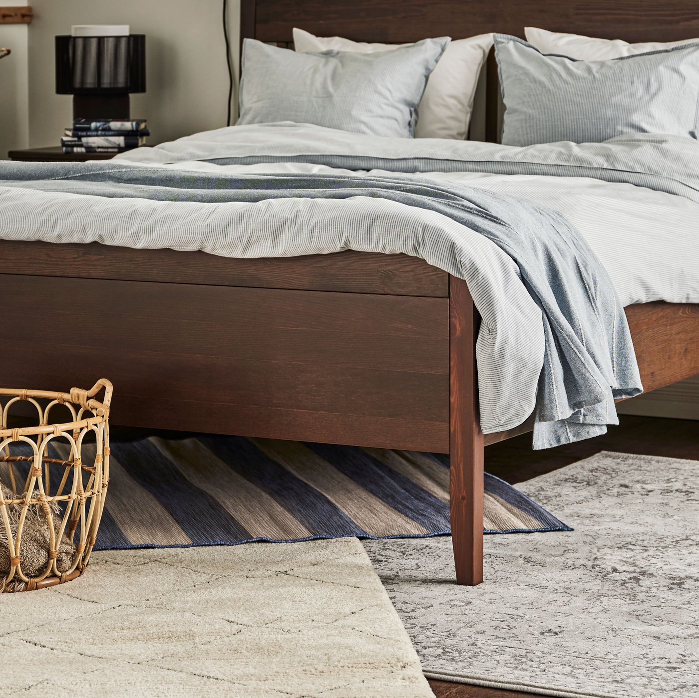 An IDANÄS bed stands in a bedroom on a floor with a TVERSTED rug, a light grey VEDBÄK rug and a VRENSTED rug.