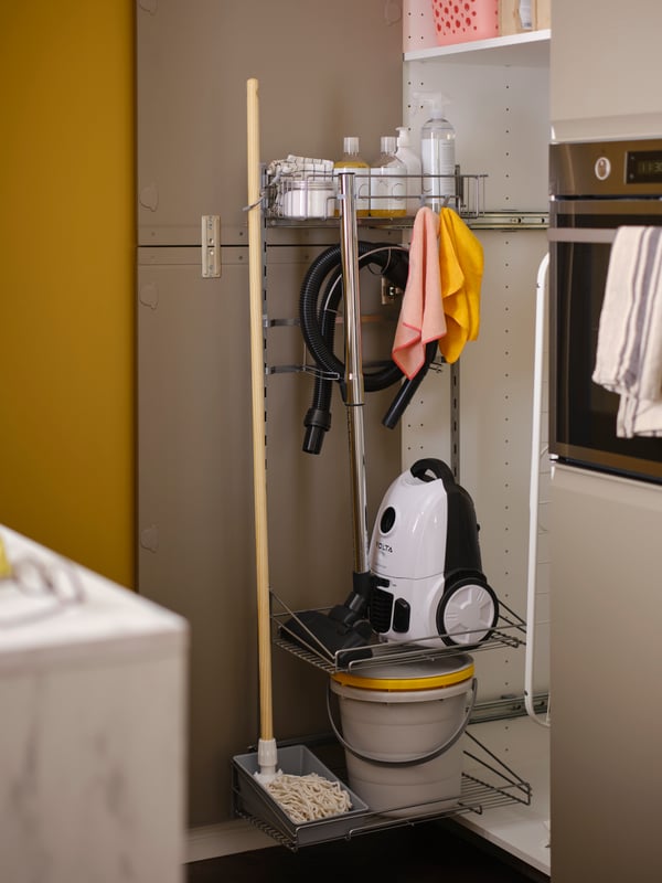 An open high cabinet showing an UTRUSTA cleaning interior holding a hoover, buckets, a mop and various other cleaning items.