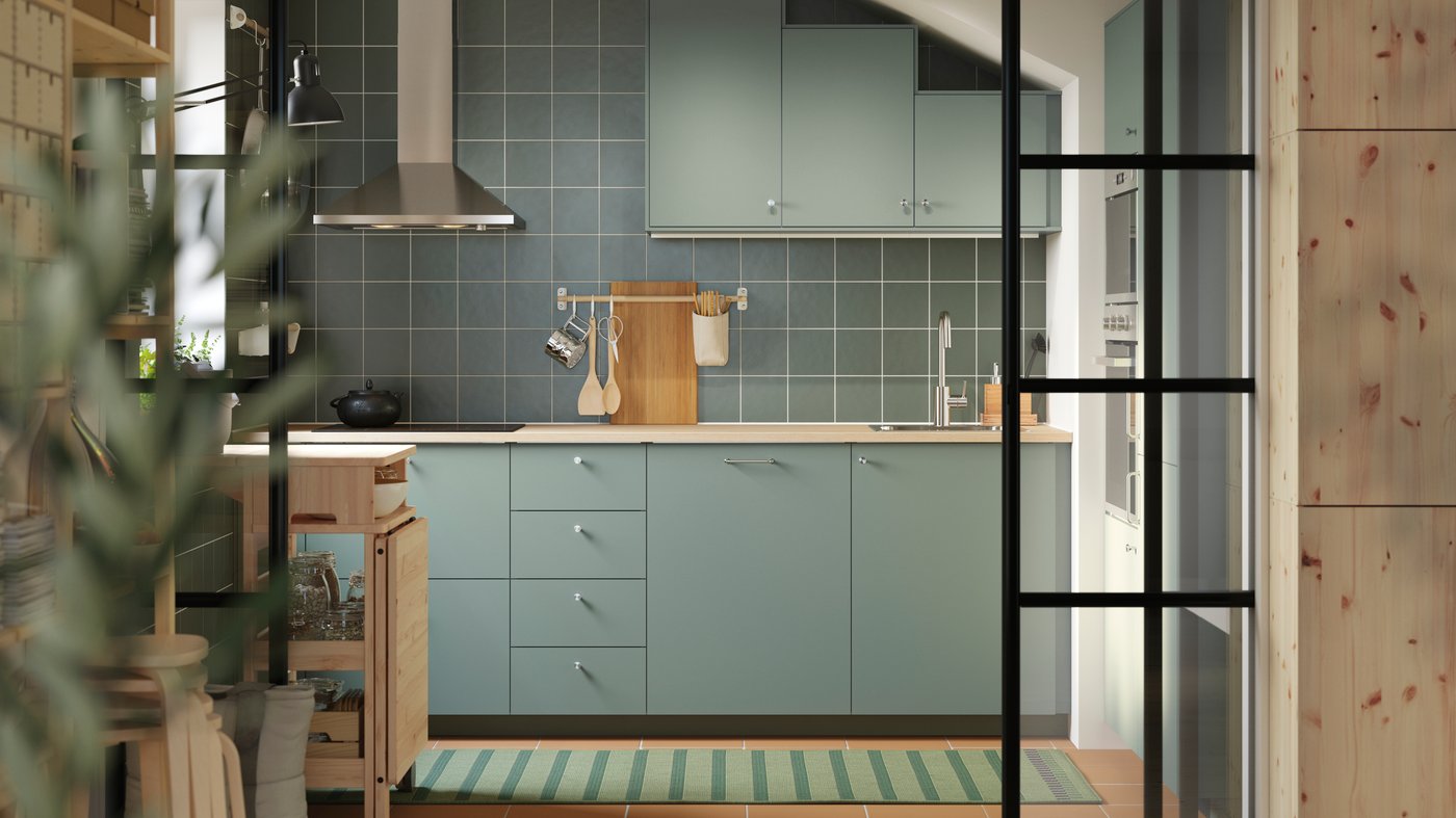 A kitchen has base and wall cabinets with matt gray green NICKEBO fronts and a RESARÖ mobile drop-leaf table with storage.