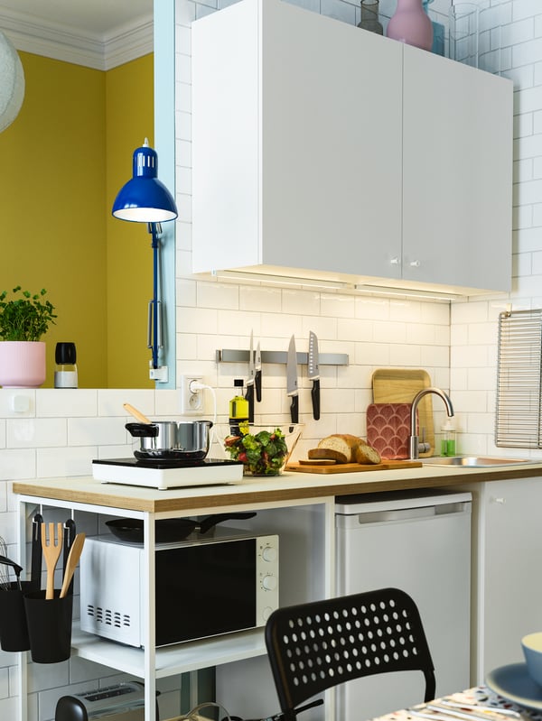 A worktop with bread and salad is lit with LED lighting strips under the cabinet and a blue lamp.