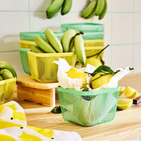Yellow and green mesh IKEA 365+ food storage baskets containing lemons and bananas.