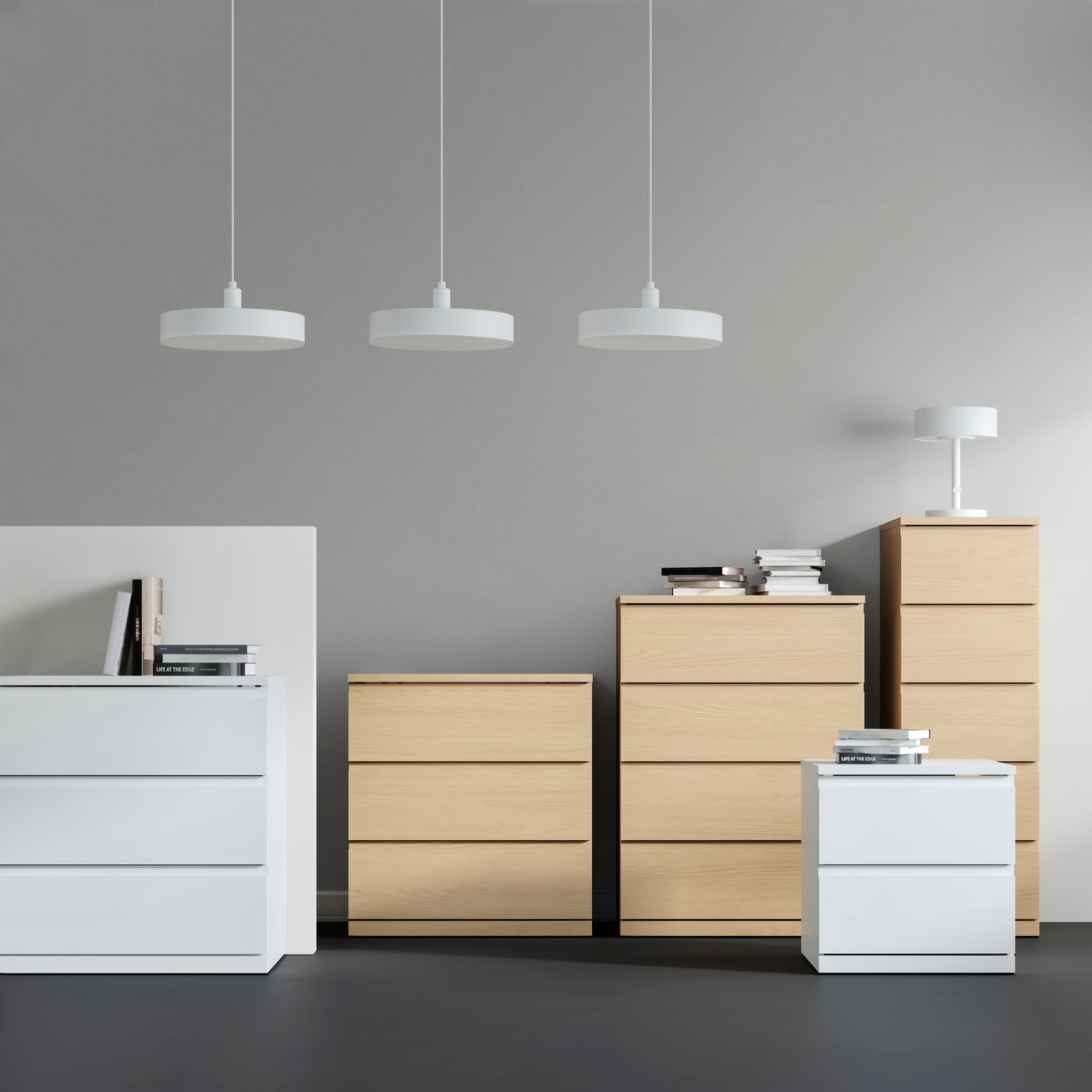 Four different sized STORKLINTA chests of drawers and a STORKLINTA bedside table are in a studio space with a grey floor.
