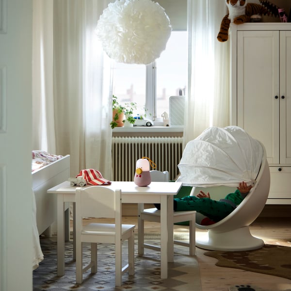 Deux chaises enfant SUNDVIK et fauteuil pivotant IKEA PS LÖMSK autour d’une table enfant SUNDVIK, près d’une armoire-penderie.
