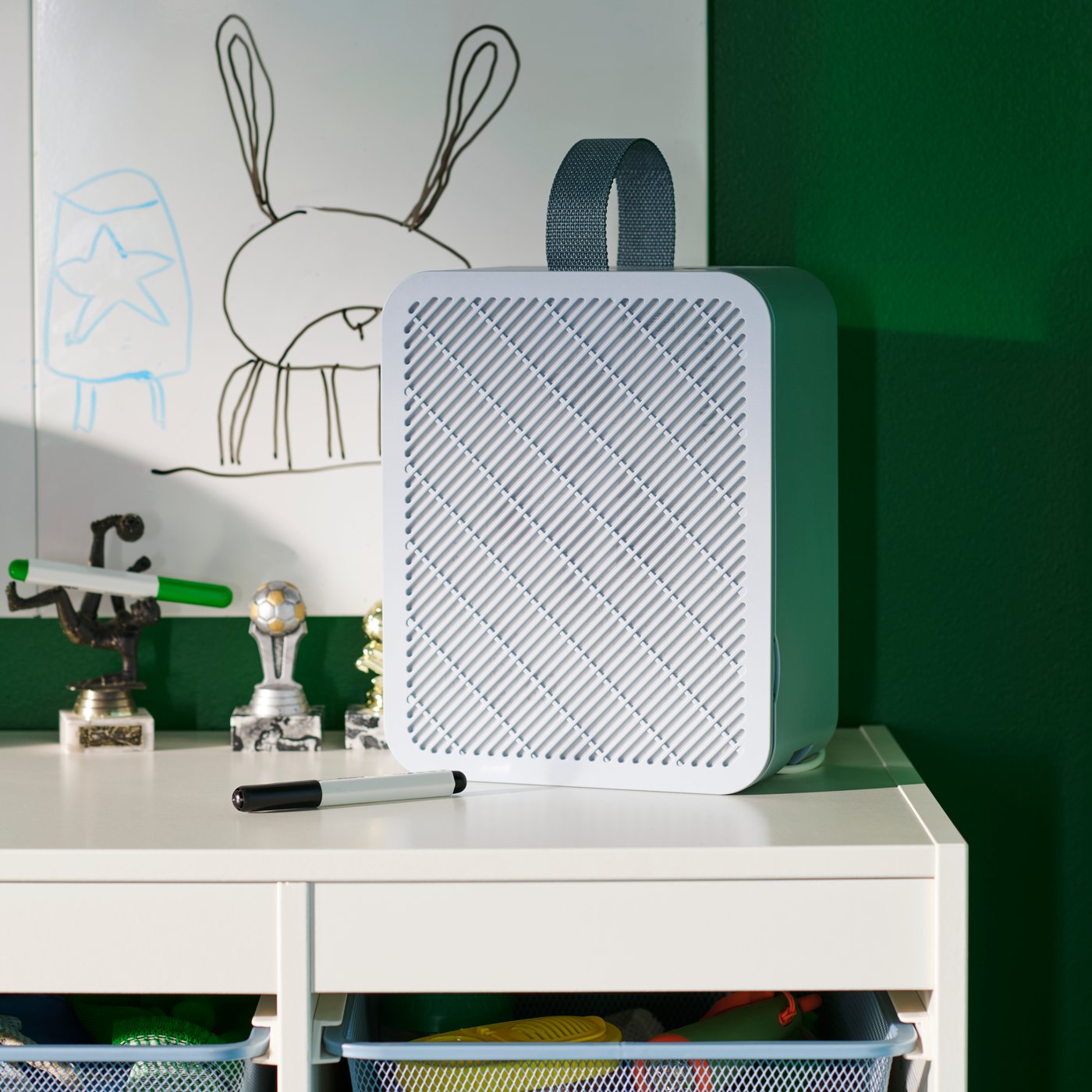 Purificateur d’air UPPÅTVIND bleu sur un bureau blanc dans une chambre d’enfant aux murs verts où un lapin est dessiné à la main.