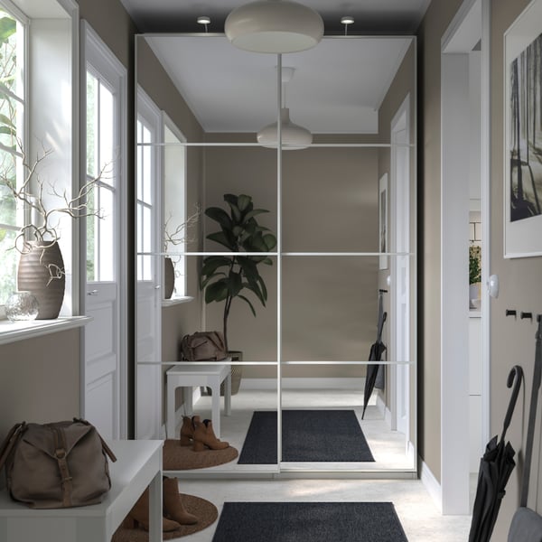 PAX wardrobe in corridor with glass sliding doors showing a reflection of the corridor with a floor runner in the middle. 