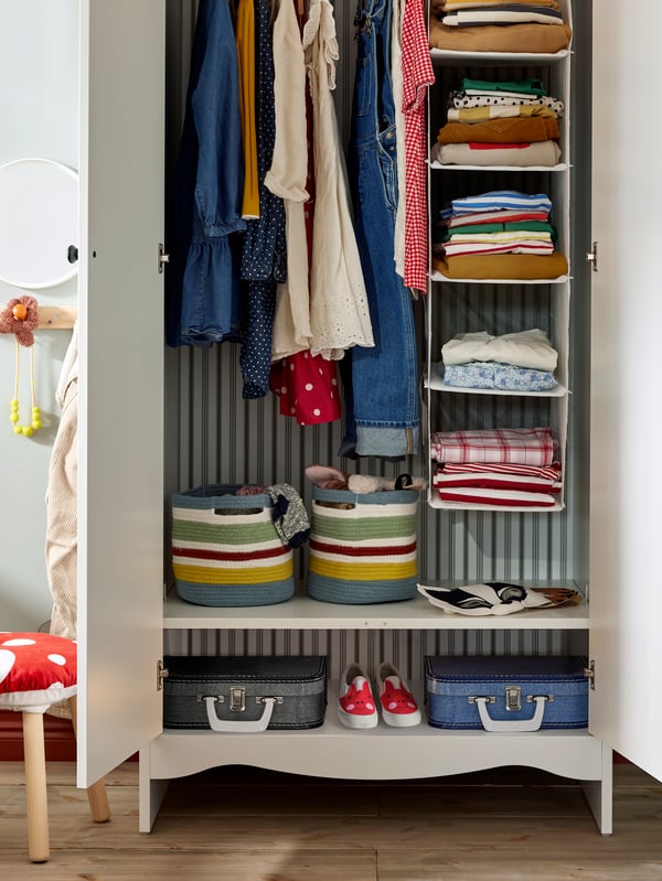 Un clóset infantil SMÅGÖRA con diferentes organizadores con ropa en el interior.