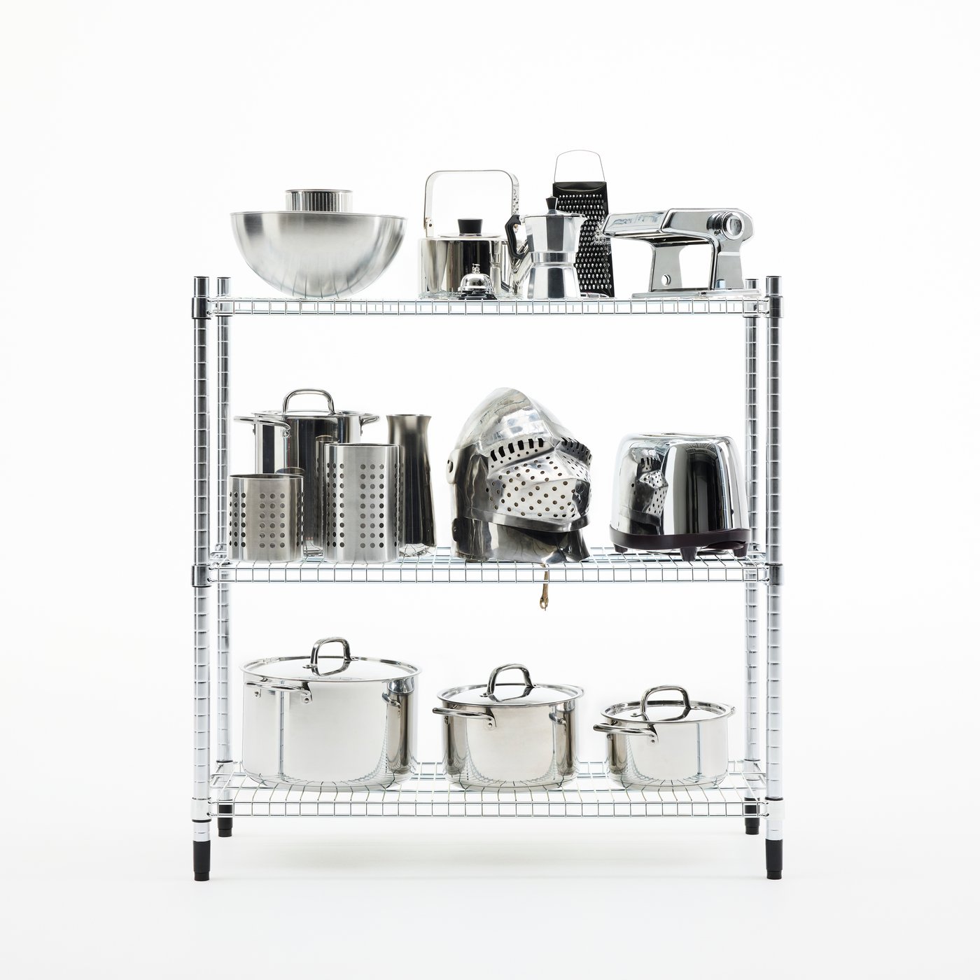 An OMAR shelving unit in galvanised steel, stacked with pots, pans, appliances – and a knight’s helmet – in shiny steel.