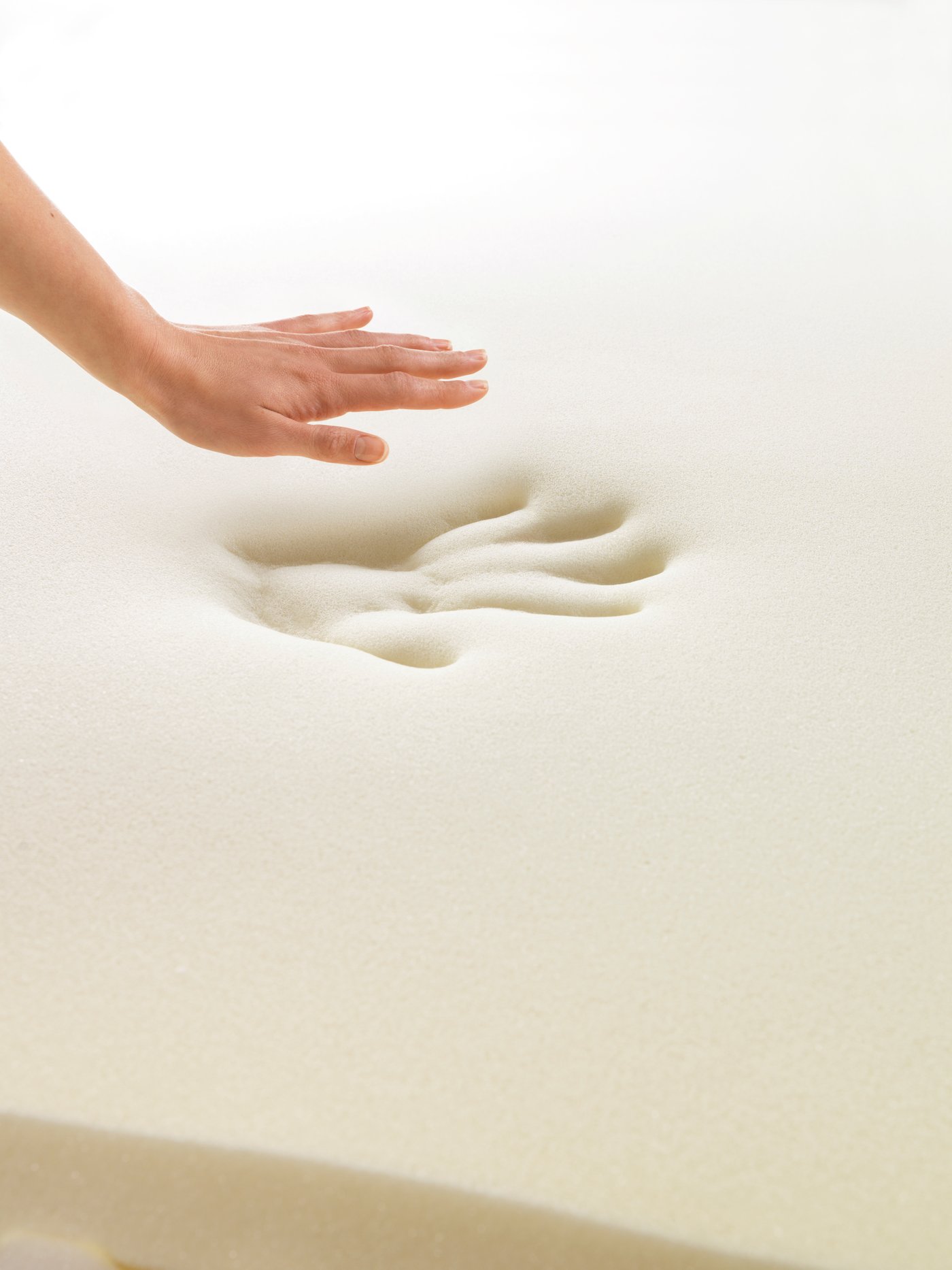 A hand that has been pressed into memory foam and lifted out, showing the imprint that it has left behind in the memory foam.