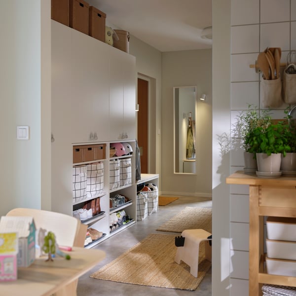 A hallway with storage cabinets and baskets that leads to a wall where the NISSEDAL mirror is mounted next to a doorway.