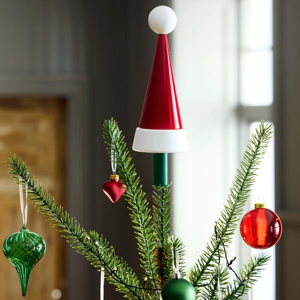 Un árbol de navidad que en la punta tiene una decoración de sombrero de santa claus