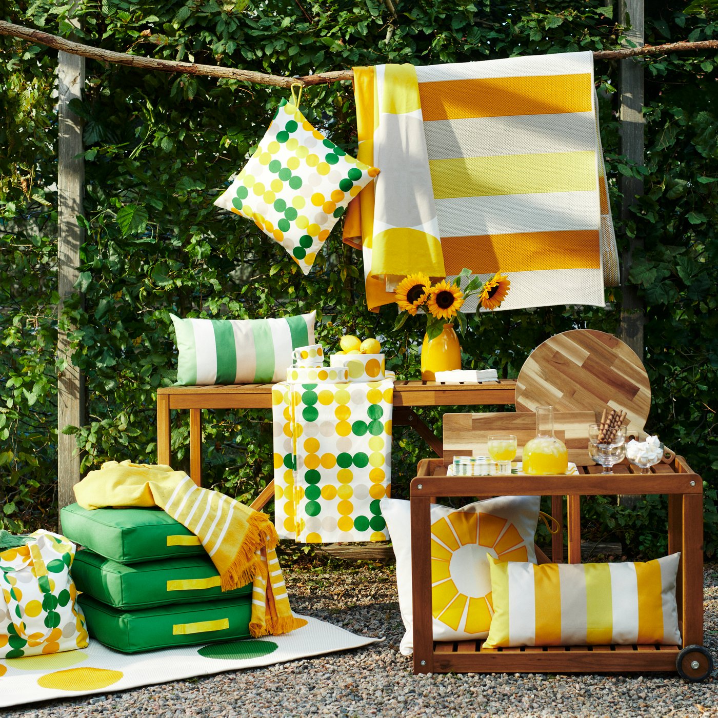 Cushions, cushion covers, rugs, tablecloths and tableware with green and yellow patterns, all from the BRÖGGAN collection.