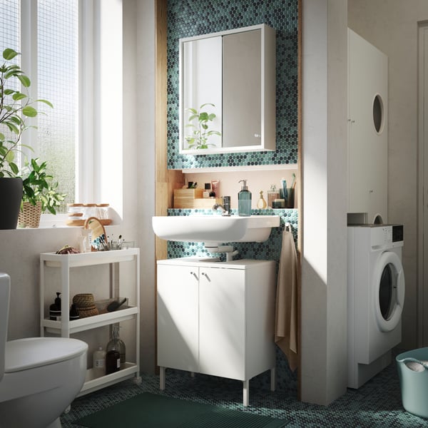 Meuble-lavabo en bois foncé doté d’un lavabo blanc à deux bacs dans une salle de bains grise aux couleurs d’accent naturelles.