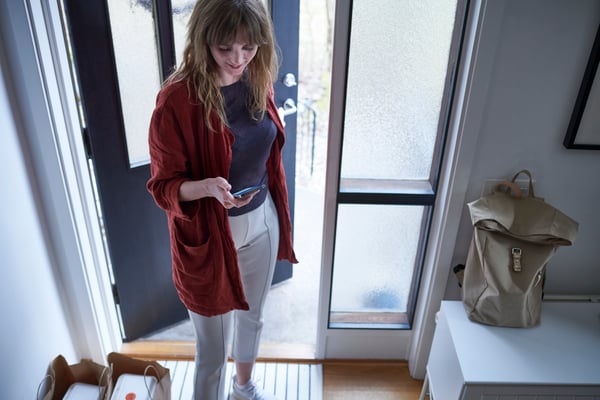 A young woman standing by her front door waiting for an IKEA delivery.