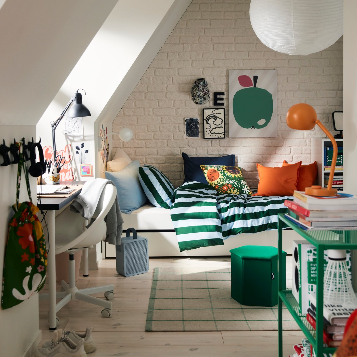 A bedroom with a SLÅNHÖSTMAL bedlinen set in dark green and light blue stripes on a bed next to a white desk and chair.