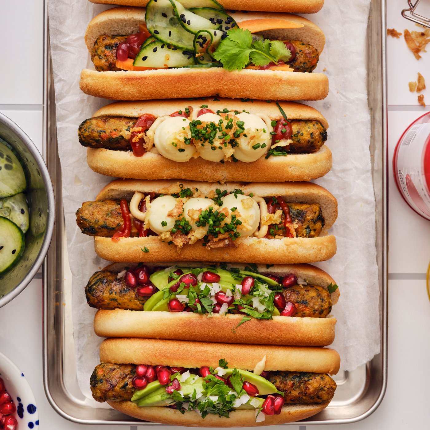 REFRÄNG vegetable hot dogs in buns on a metal tray are topped with ALLEMANSRÄTTEN mashed potatoes and other ingredients.