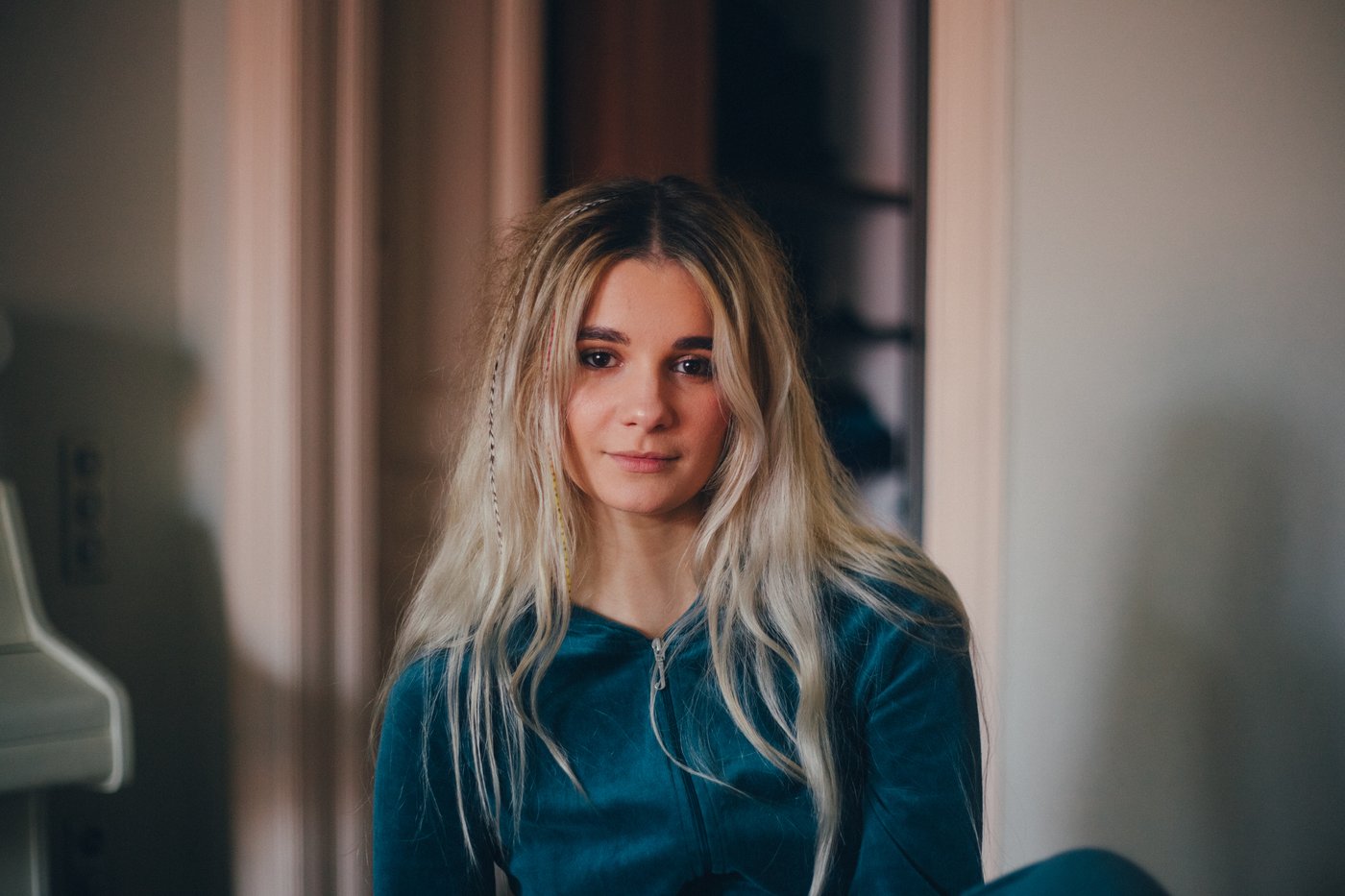 Yana kod kuće u zelenom duksu s kapuljačom s mnogo tankih pletenica u kosi.