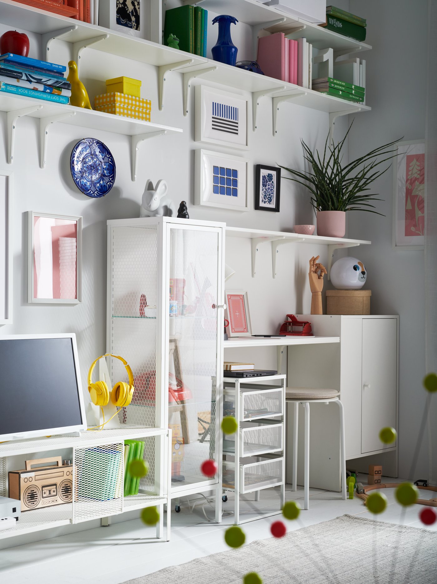 Farbenfrohes IKEA Arbeitszimmer mit offenen Regalen, einem kompakten Schreibtisch und dekorativen Accessoires. Auffällige Farbakzente durch Bücher, Vasen und Bilder sorgen für eine kreative und inspirierende Arbeitsatmosphäre.
