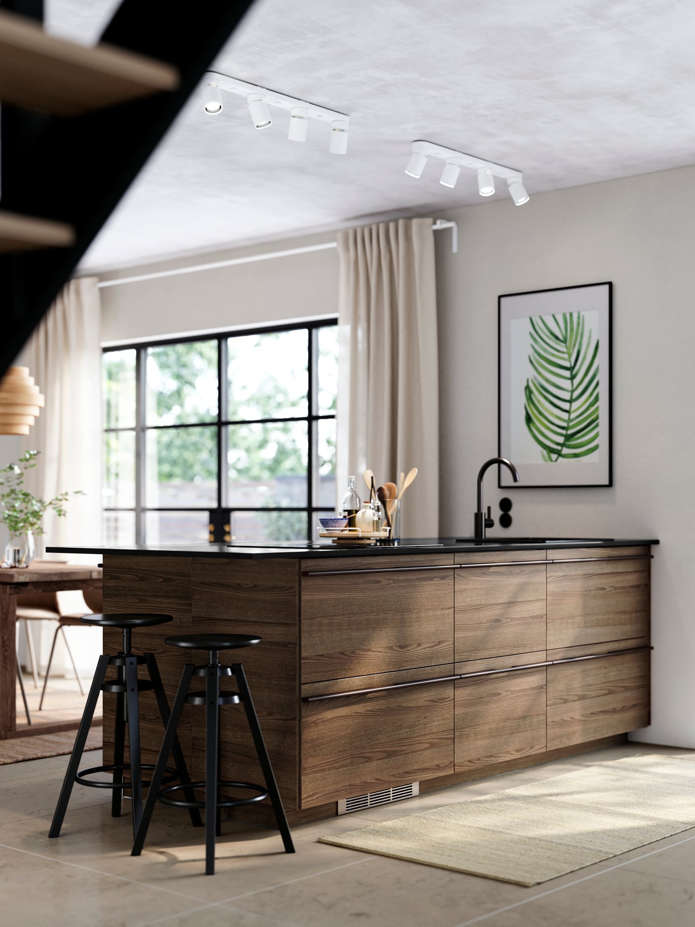 A kitchen island featuring STENSTA dark brown ash veneer fronts, black bar stools, a black tap, and large windows.