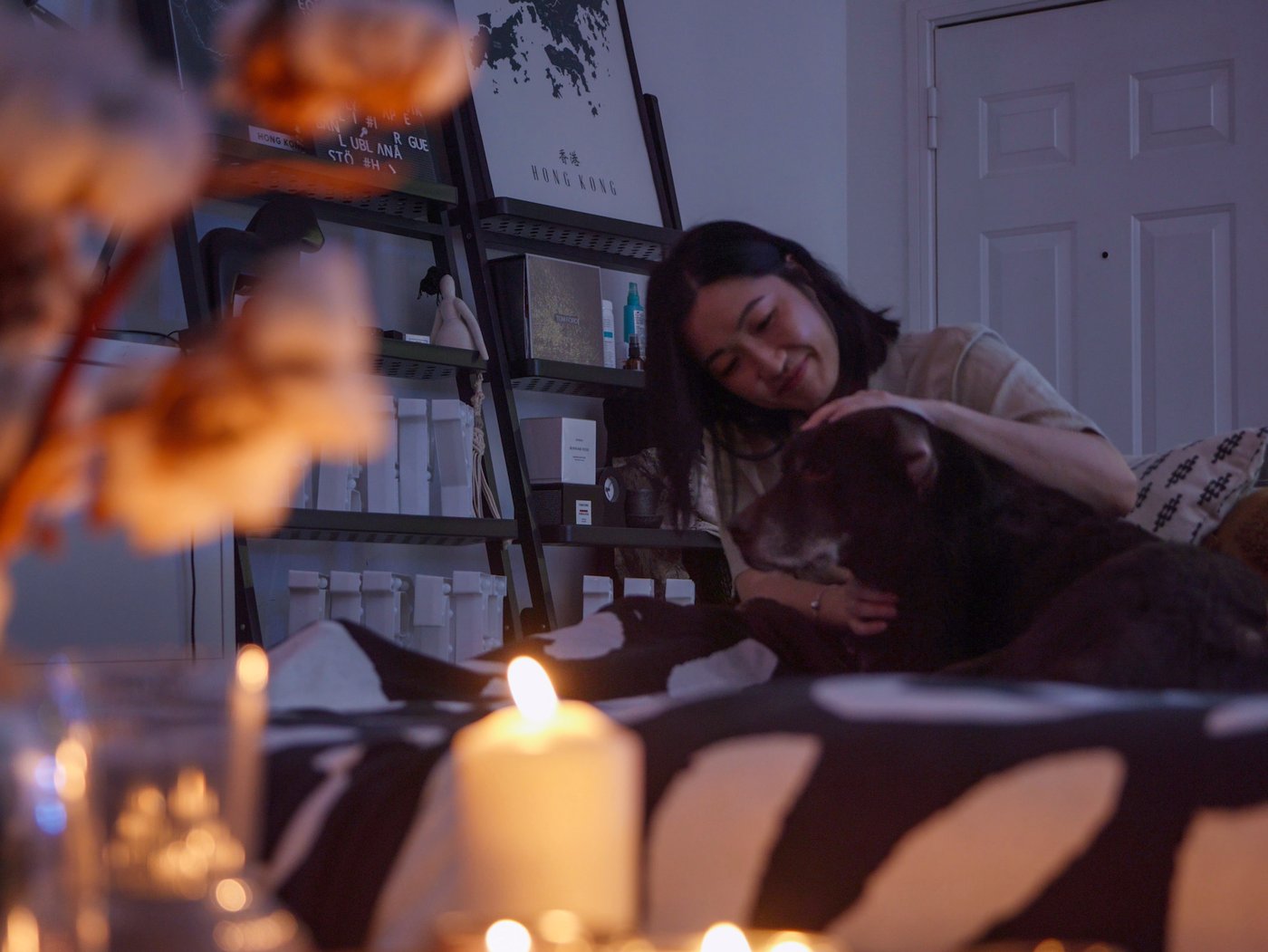 A woman and a dog relax in front of a table full of lit candles.
