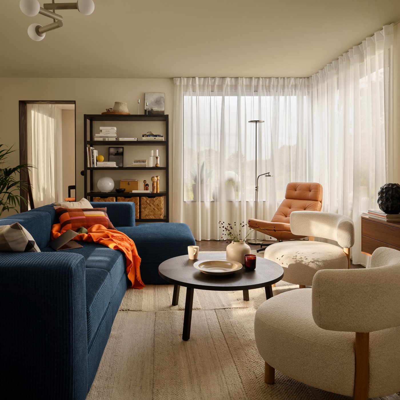 A living room with a dark-blue JÄTTEBO four-seat sofa with chaise longue next to STOCKHOLM 2025 armchairs and coffee table.