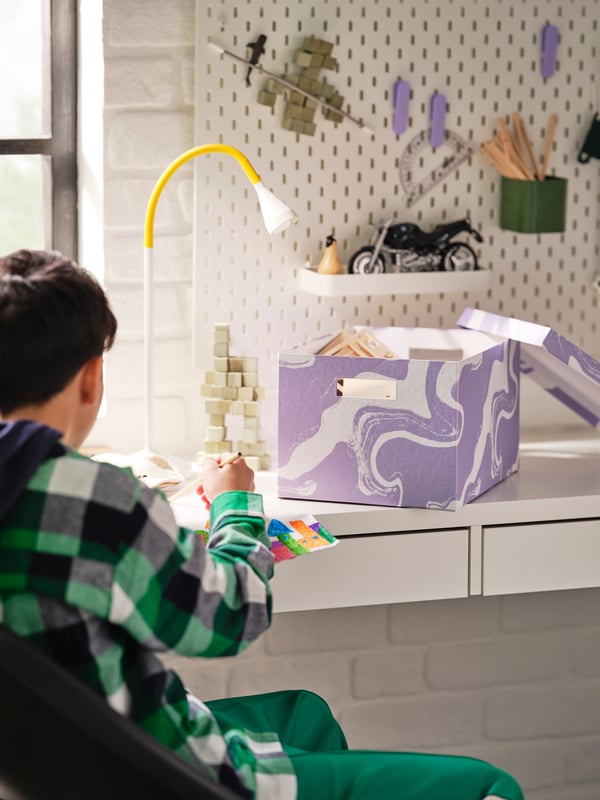 A patterned/lilac white TJENA storage box with lid in the childrens room