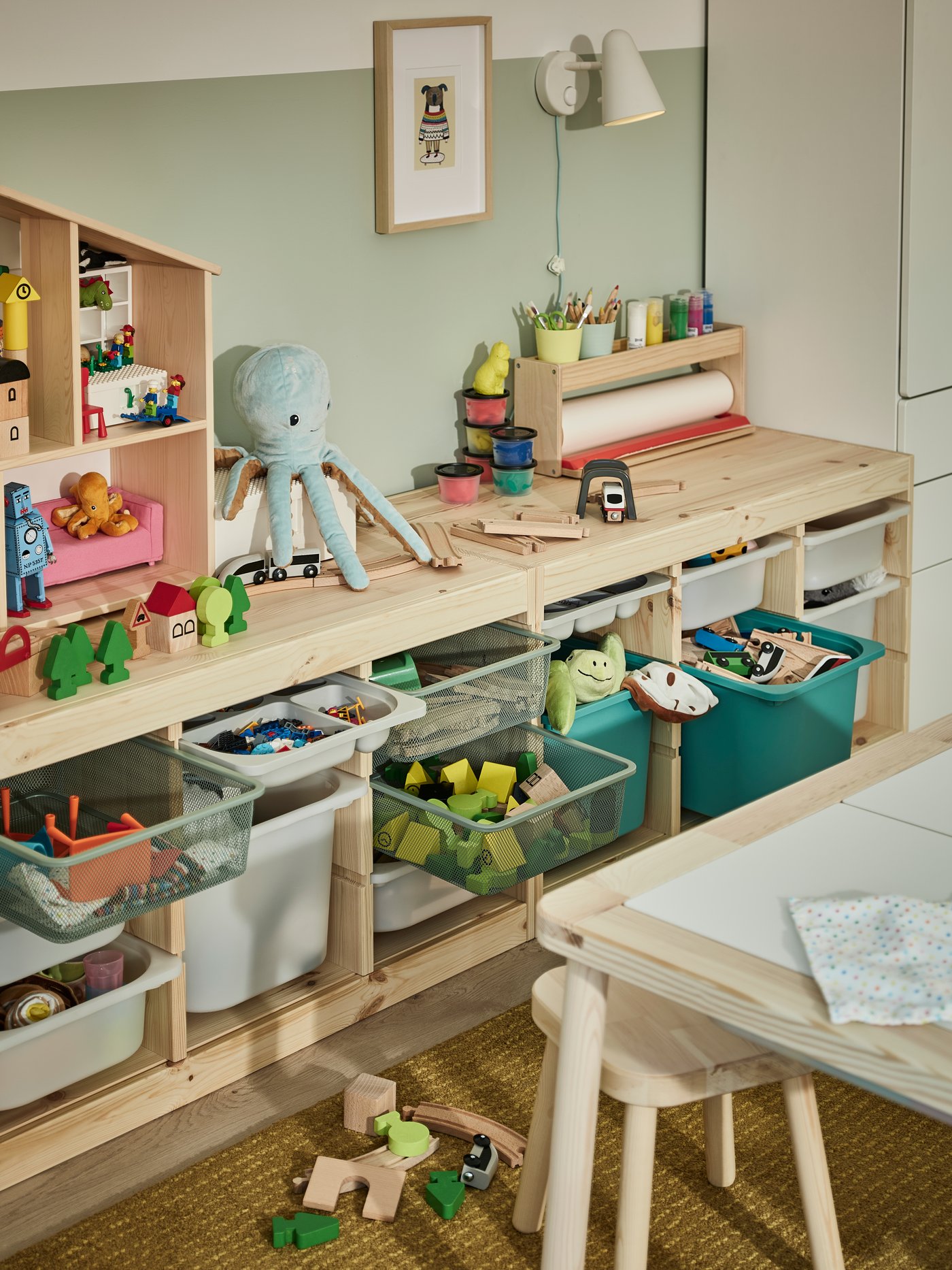 En un espacio infantil hay una mesa de madera FLISAT y un mueble TROFAST con cajas 