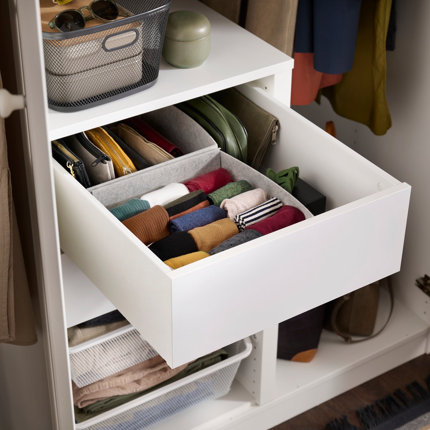 A close-up of an open drawer in a white PAX wardrobe containing clothes neatly folded in PURRPINGLA boxes.
