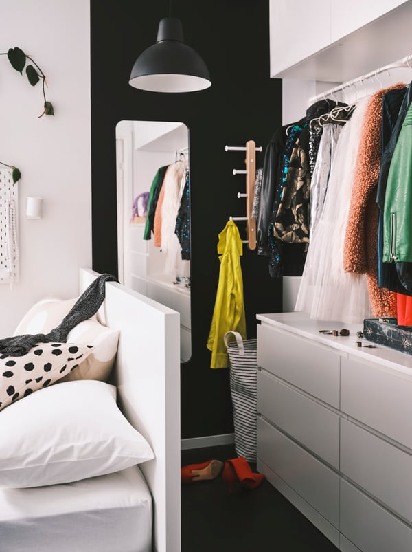 Zwei MULIG Kleiderstangen sind über einer weißen MALM Kommode mit 6 Schubladen an der Wand angebracht. Diese steht hinter einem weißen MALM Bettgestell.