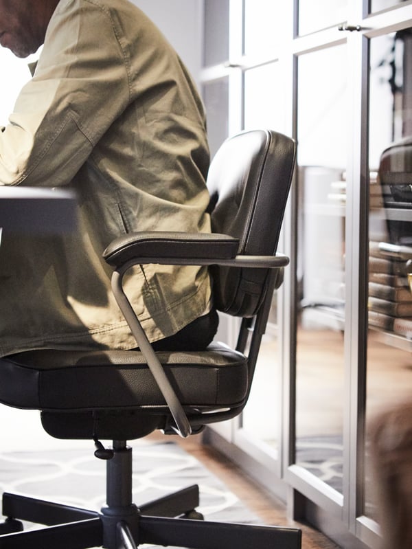 A man sitting on a ALEFJÄLL office chair in front of a BILLY bookcase.