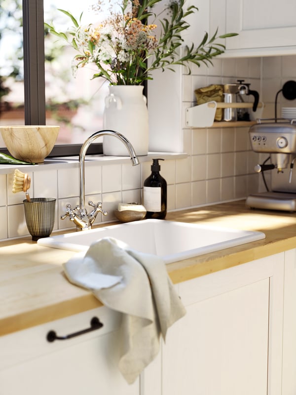 Vista superior de una cubierta de cocina de madera natural. Bajo la encimera se ve un cajón abierto con utensilios de cocina ordenados en un organizador VARIERA. 