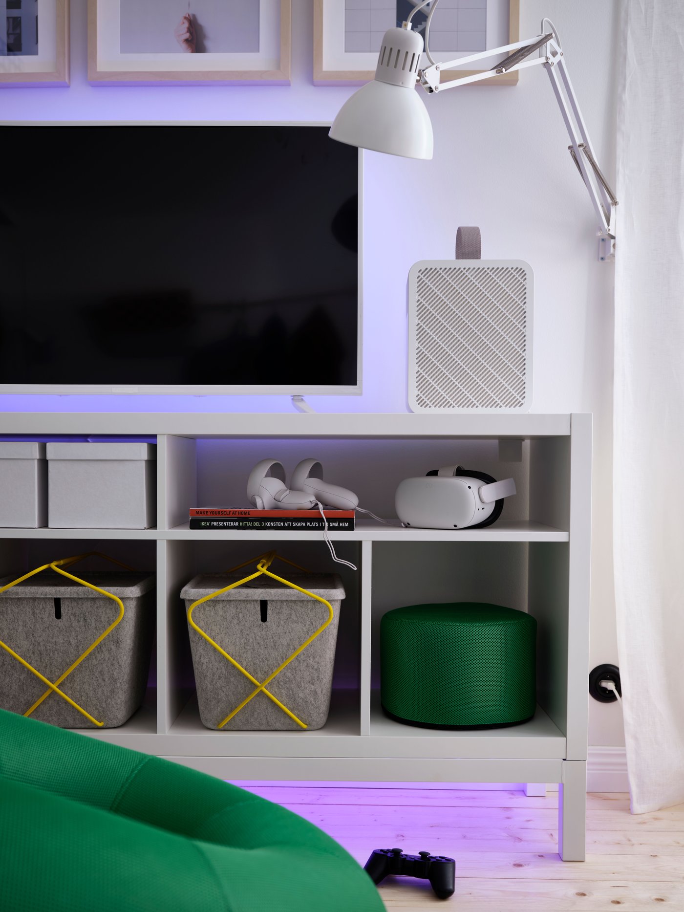 An unseen ORMANÄS LED lighting strip gives off a purple glow below and behind a console gaming setup on a white TV bench.