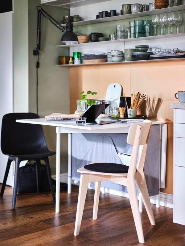 An anthracite ODGER chair and ash LISABO chair at a KALLHÄLL gateleg table with storage, set up as a workspace with a laptop.