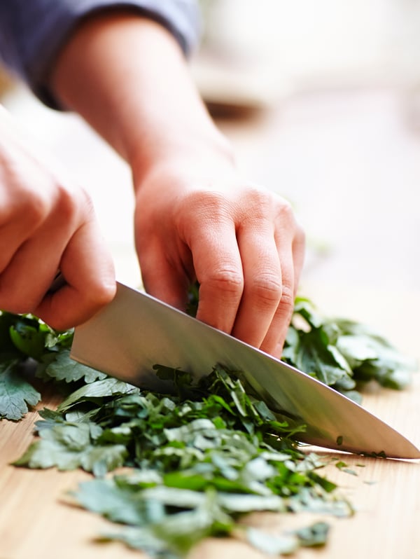 A person using a chopping board and an IKEA 365+ cook’s knife.