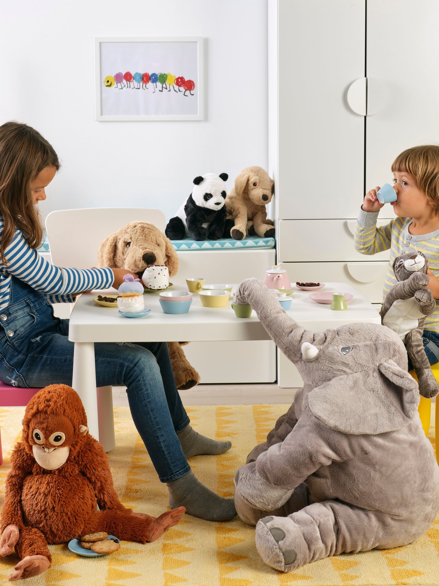 Two children playing with stuffed animals at a white table, labeled “Gifts for children”