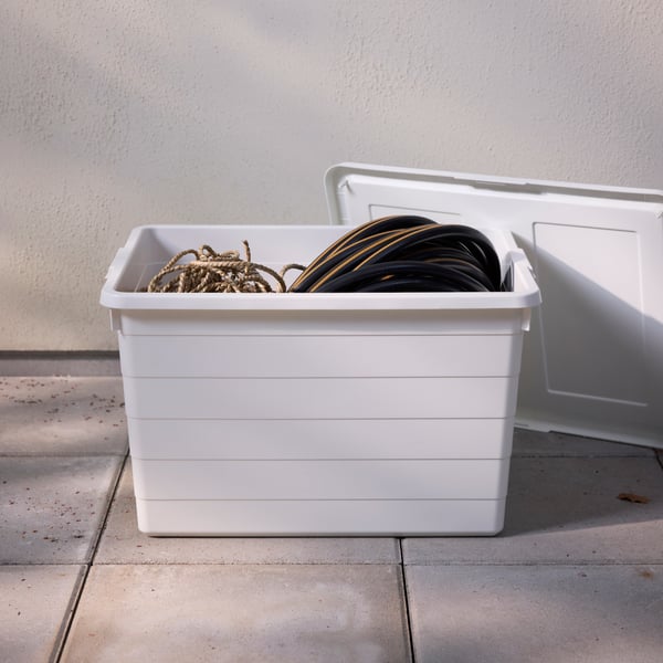 A white SOCKERBIT box with lid containing some rope and a garden hose stands on a terrace on a sunny day.