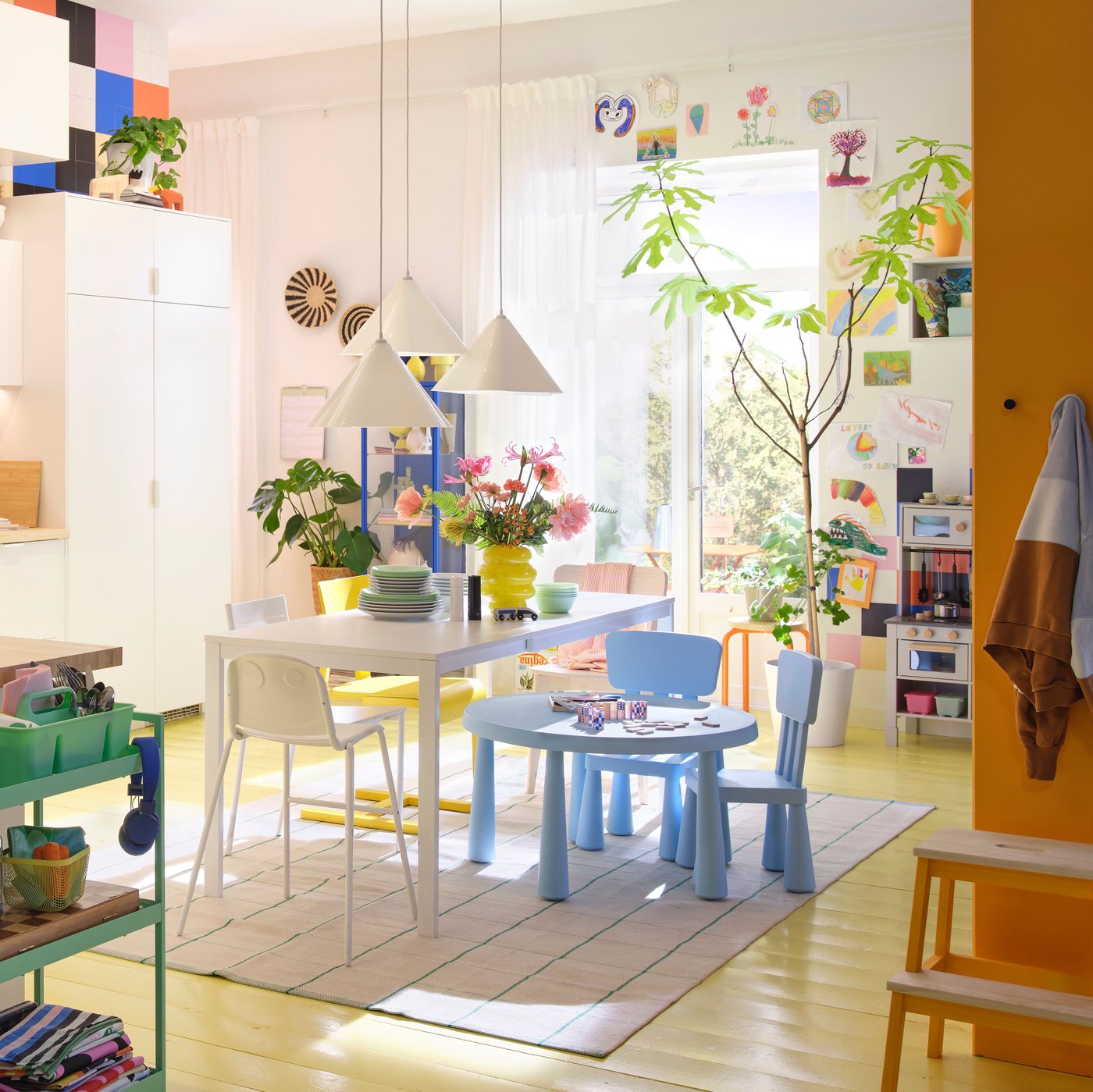 A bright kitchen featuring white VEDDINGE doors, vibrant decor, a wooden table, and potted plants.