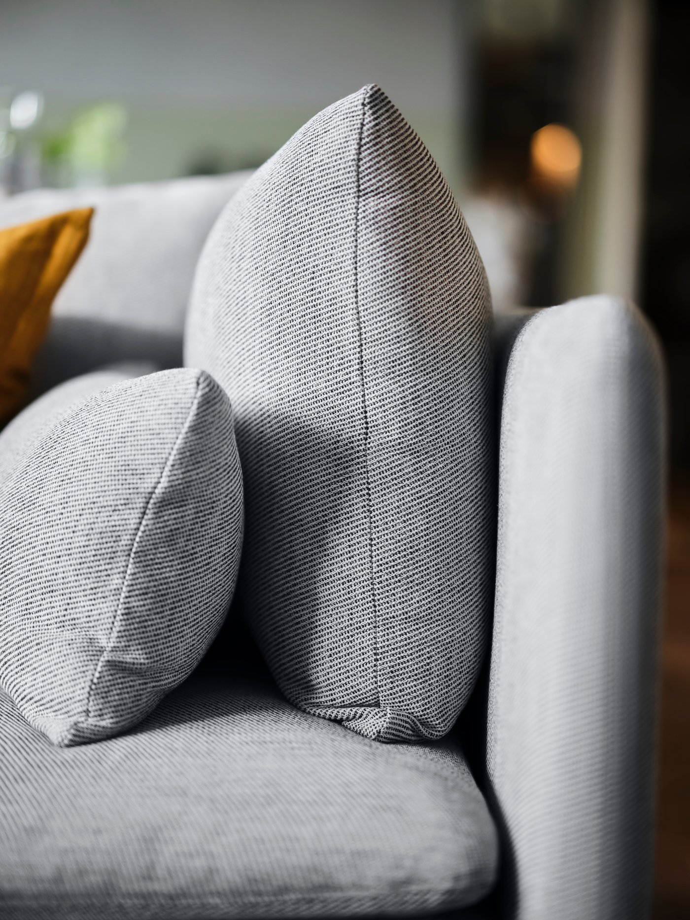 A close-up of the armrest of a beige-brown SÖDERHAMN sofa with two cushions propped against the side panel.