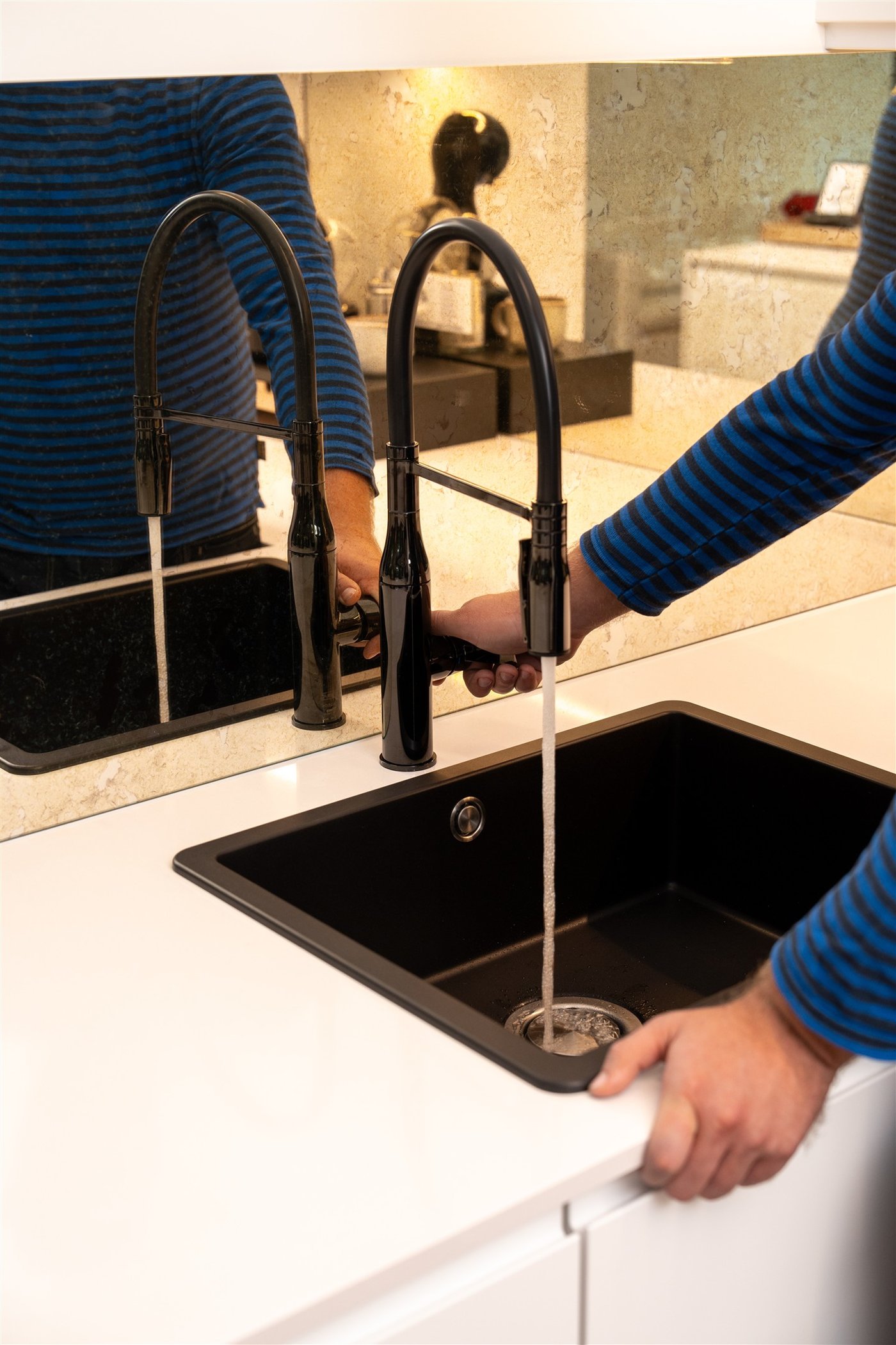 Ein IKEA Mitarbeiter testet einen Wasserhahn in einer weißen IKEA Küche