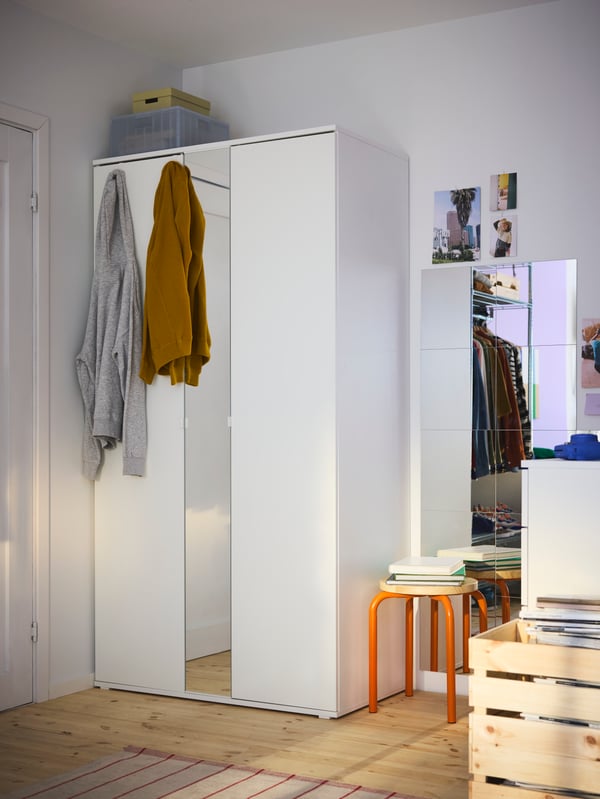 VIHALS wardrobe in white with a mirror, plus extra mirrors on the wall to the right. A pile of stackable stools next to it.