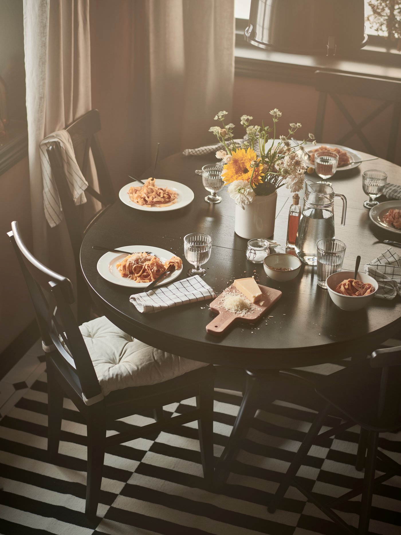 Dining room with a round, black dining table set with plates and glasses