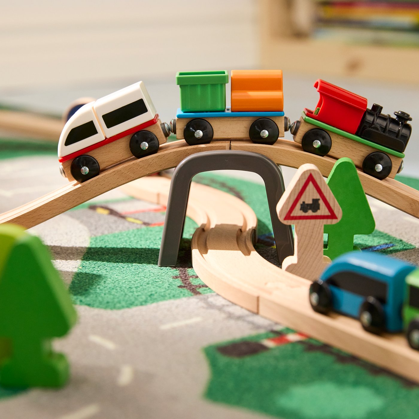 Close-up of LILLABO train bridge set with one train passing on top of bridge and one on the rail below. All on LILLABO rug.