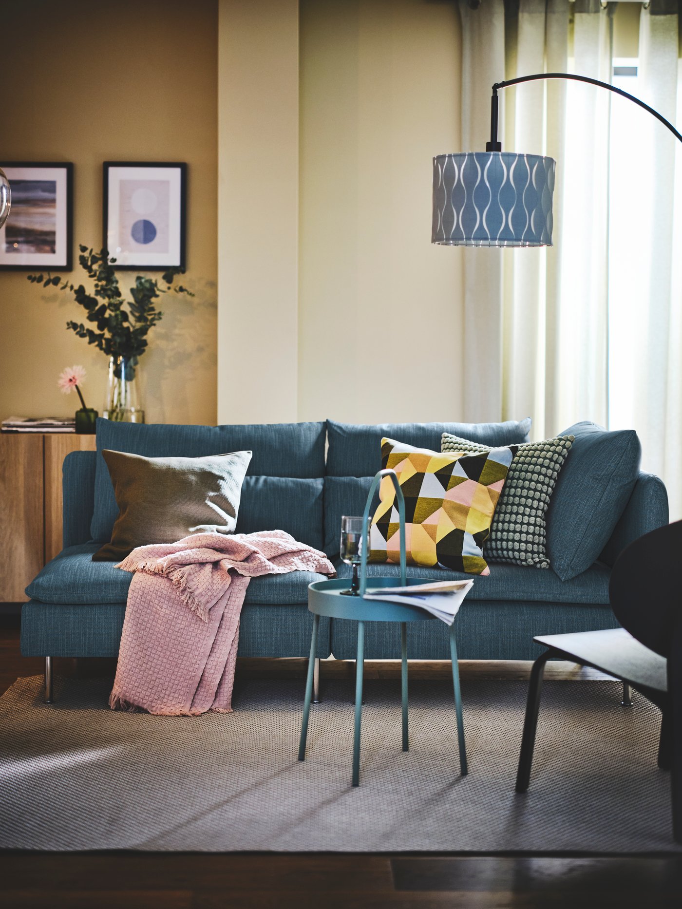 A Hillared dark blue SÖDERHAMN sofa with multicolour SVARTHÖ cushion cover in the living room.