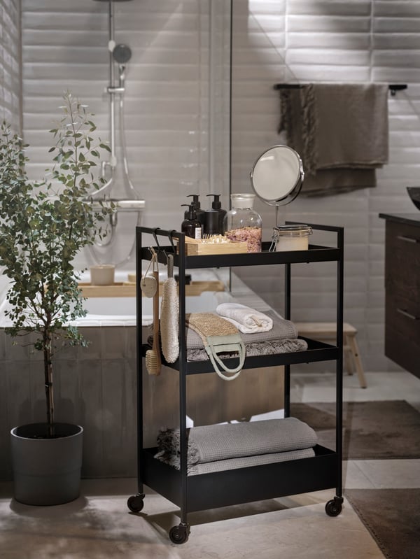 En rullevogn på et badeværelse er fyldt med alt fra sæbe til håndklæder og scrub til wellness hygge.