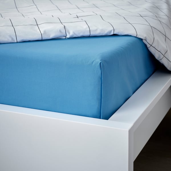 Un drap-housse bleu sous une housse de couette à carreaux.
